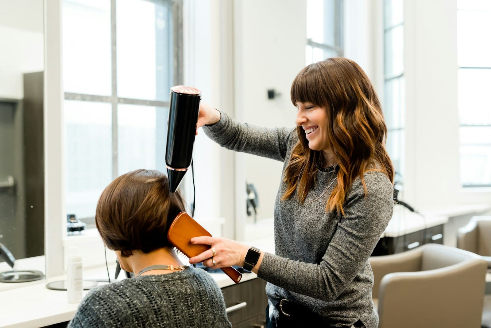 A MARMO stylist finishing a blowout in daylight at the studio window