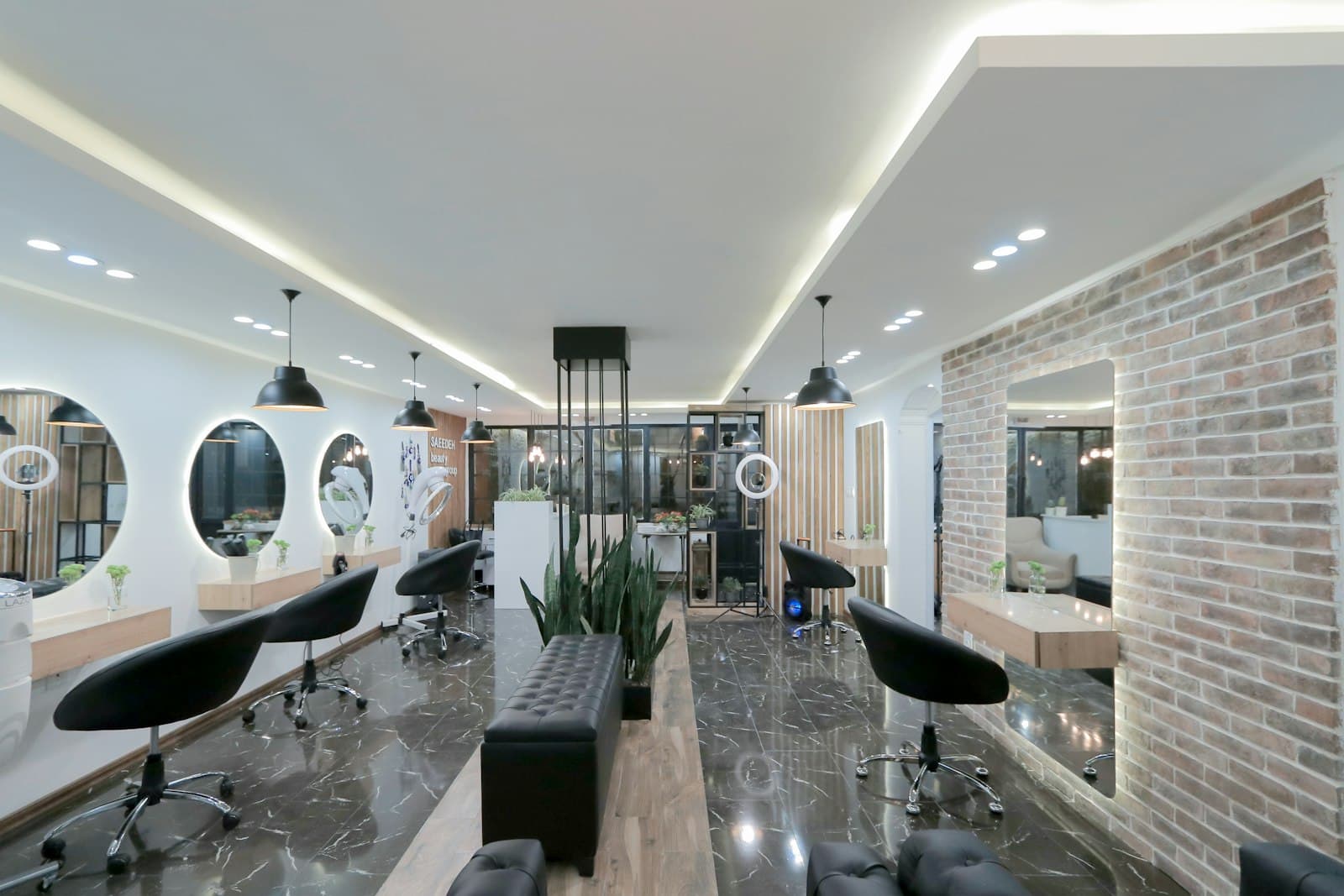 The MARMO studio interior in daylight: long marble counter, round mirrors, brick wall